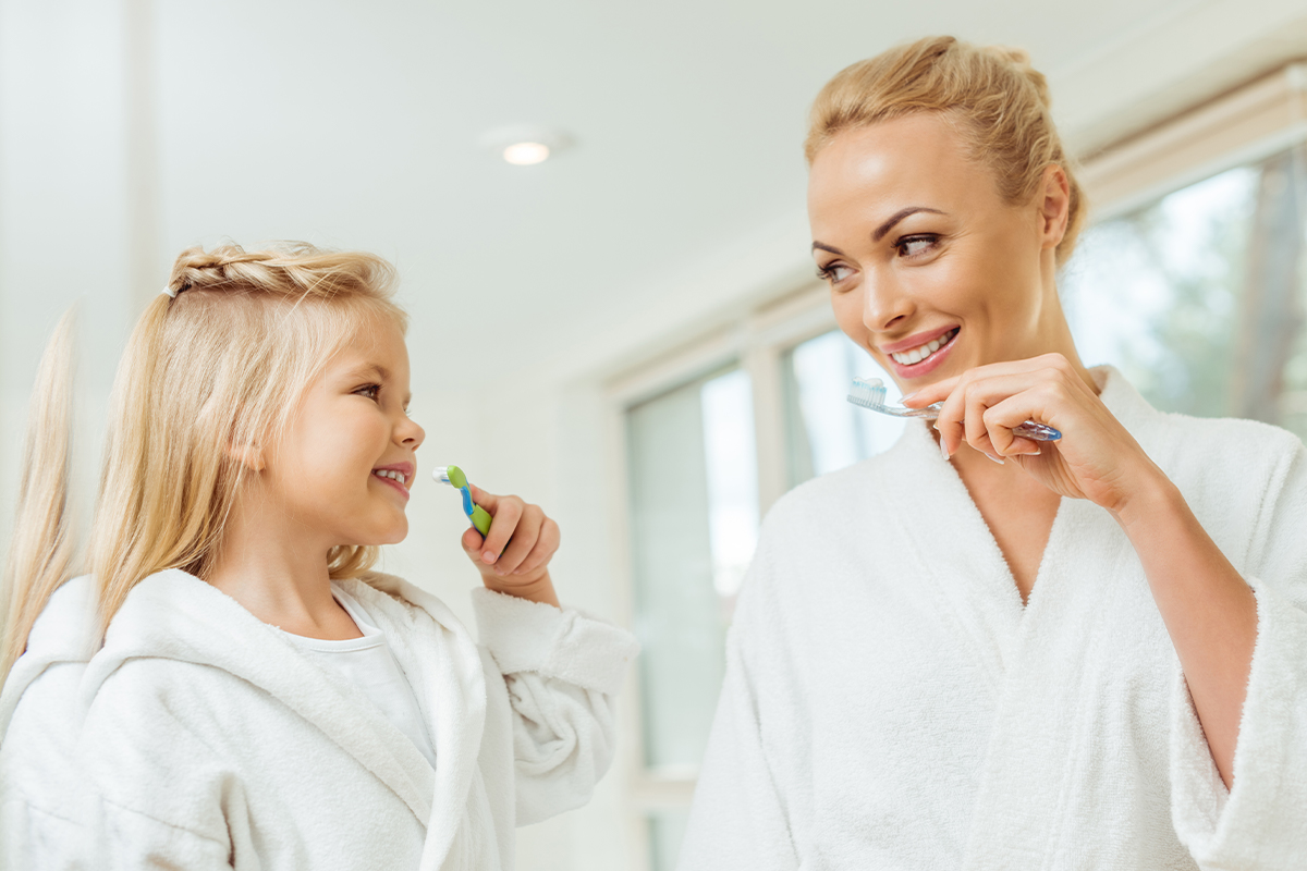 Beautiful woman and kid brushing their teeth